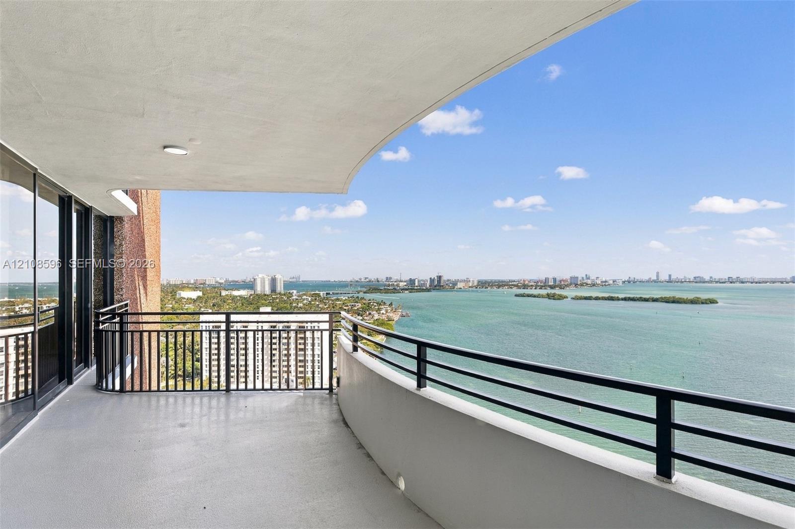 Curved open-air balcony featuring a concrete floor, black metal railing, and recessed ceiling lighting