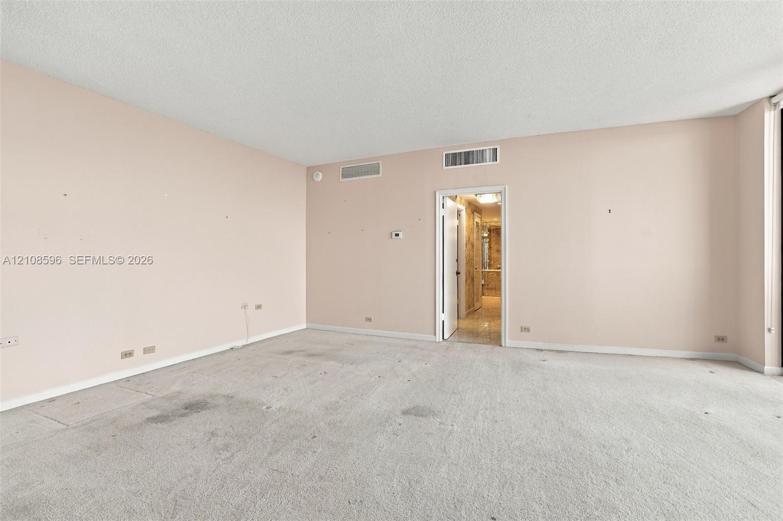 Expansive interior room featuring neutral wall finishes, plush carpeting, and recessed ceiling HVAC registers