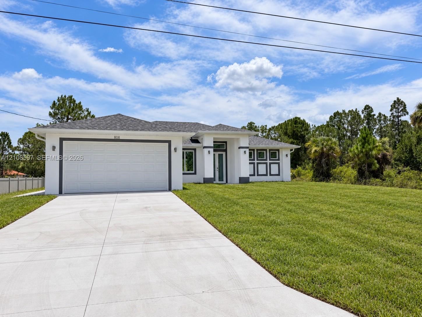 Single-story exterior featuring white stucco siding, a grey shingled hip roof, a concrete driveway, and an attached two-car garage