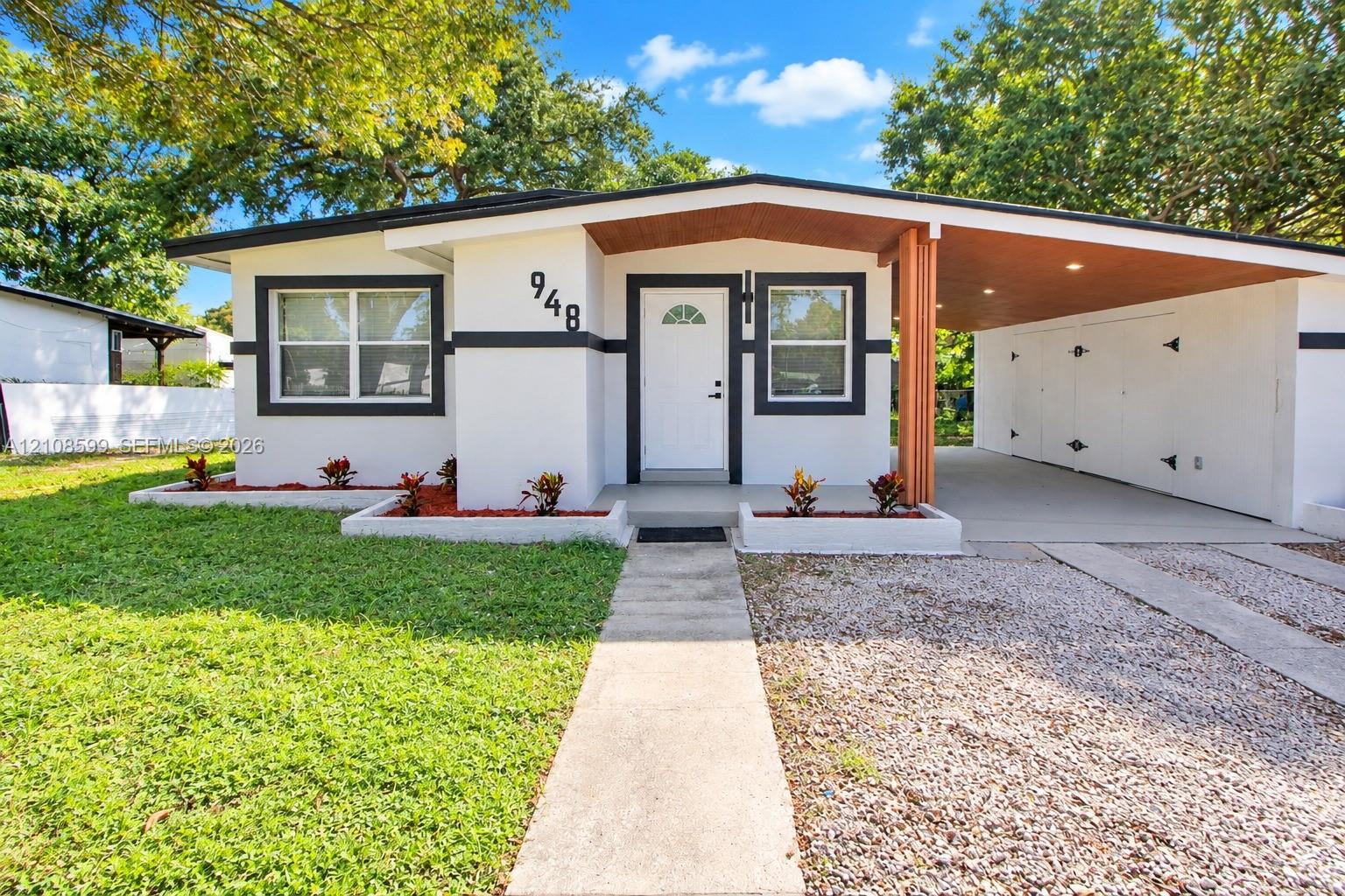 Mid-century exterior featuring a recessed entry, covered carport, wood-paneled ceiling, concrete walkway, and raised planting beds Mid-century exterior featuring a recessed entry, covered carport, wood-paneled ceiling, concrete walkway, and raised planting beds