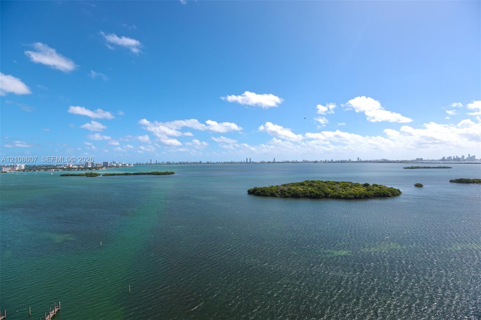 Expansive coastal waterscape featuring multiple mangrove islands and a distant skyline