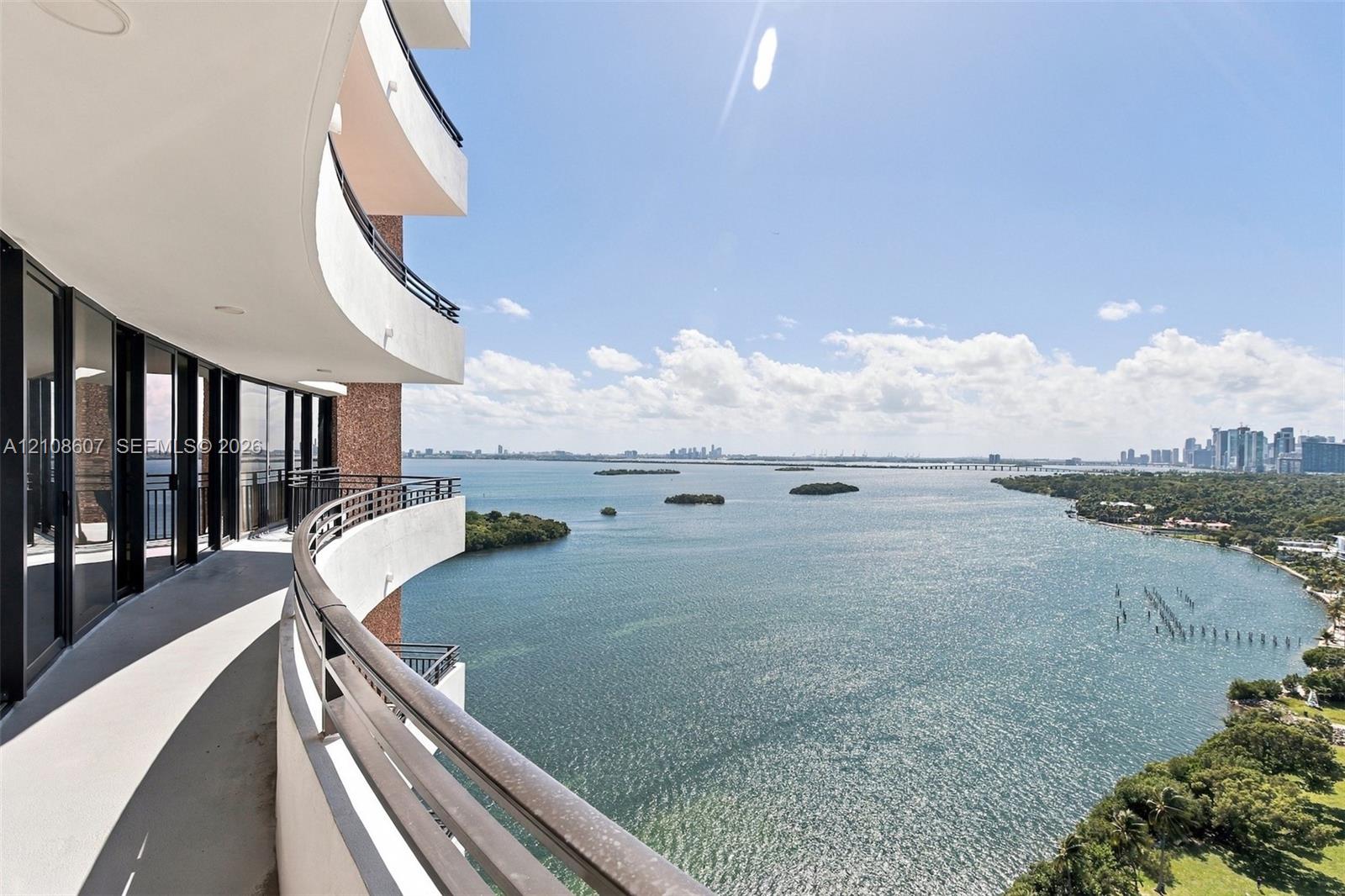 Curved concrete balcony featuring black metal railings and full-height glass sliding doors