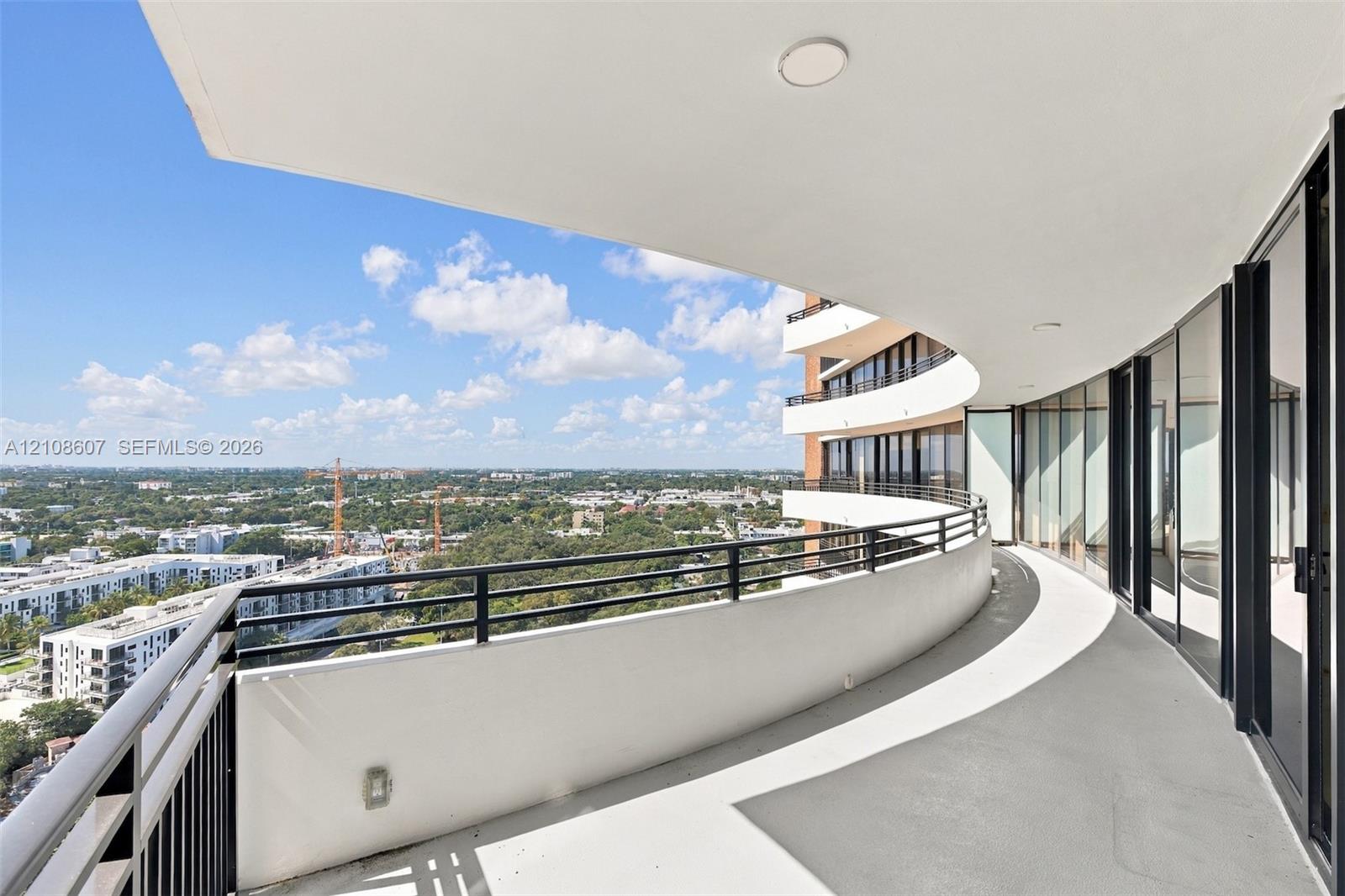 Curved balcony featuring metal railings, concrete flooring, recessed ceiling lighting, and floor-to-ceiling glass wall panels