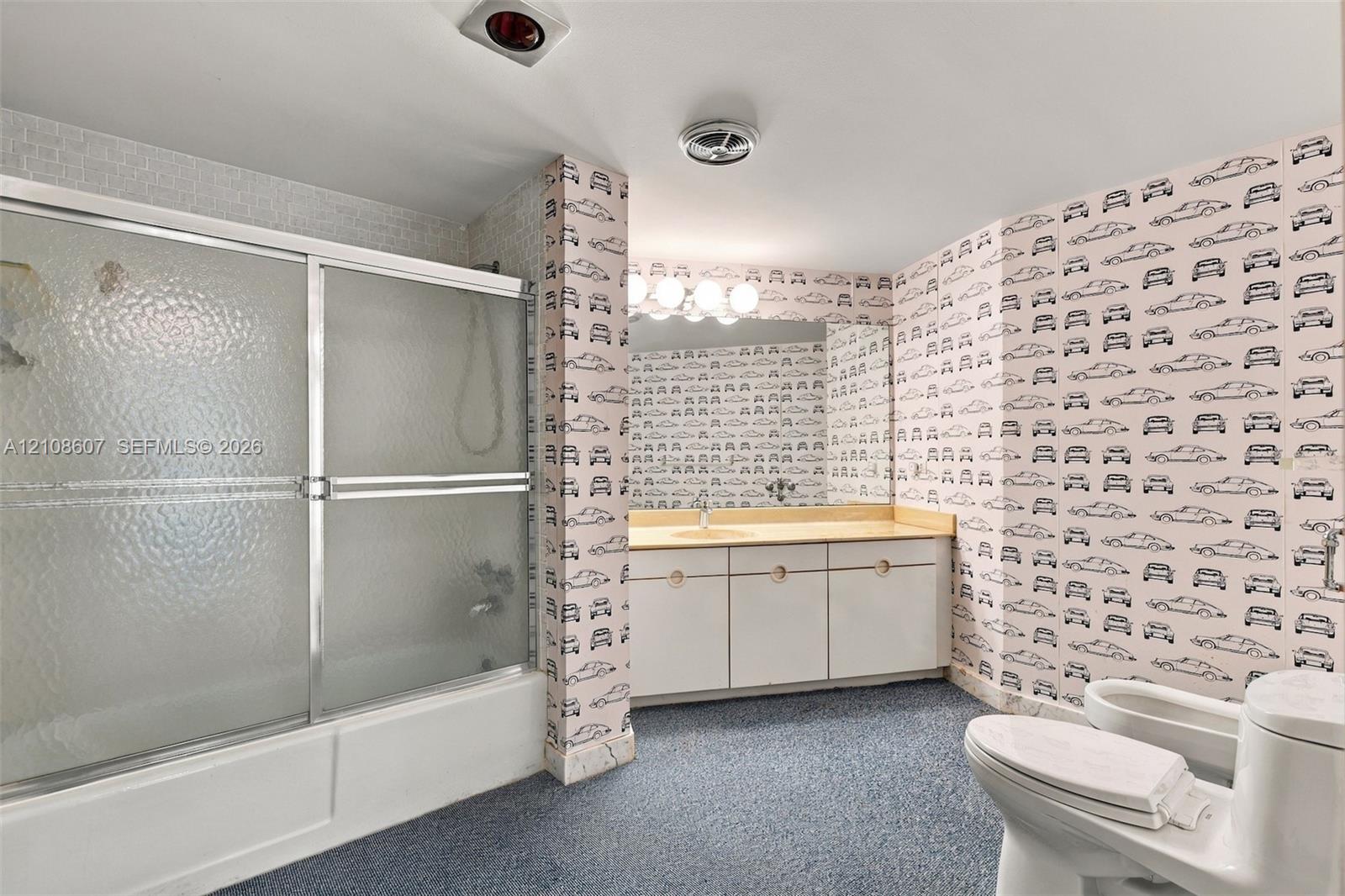 Bathroom featuring a sliding glass shower door, built-in vanity with countertop, large wall-mounted mirror, and multi-bulb light fixture