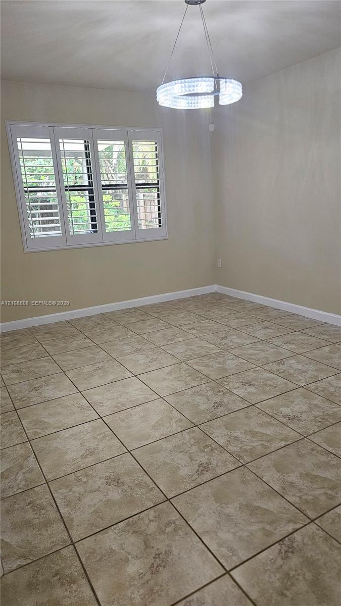 Ceramic tile flooring, crown molding, multi-panel window with plantation shutters, and a circular crystal pendant light fixture