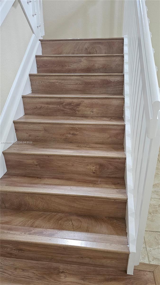 Staircase featuring wood-finish treads and white-painted railings
