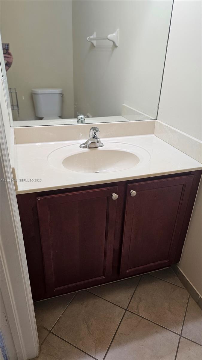 Bathroom vanity featuring a dark wood-finish cabinet, integrated basin, countertop with matching backsplash, and tile flooring