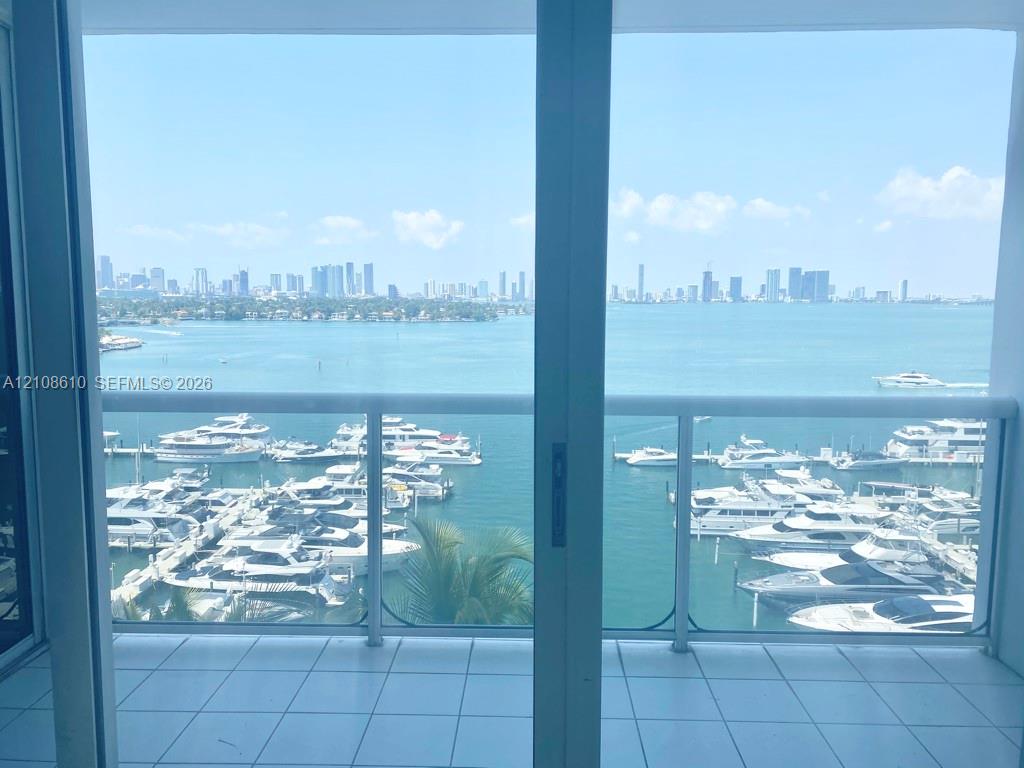 Balcony featuring ceramic tile flooring, a white metal frame, and glass panel railing Balcony featuring ceramic tile flooring, a white metal frame, and glass panel railing