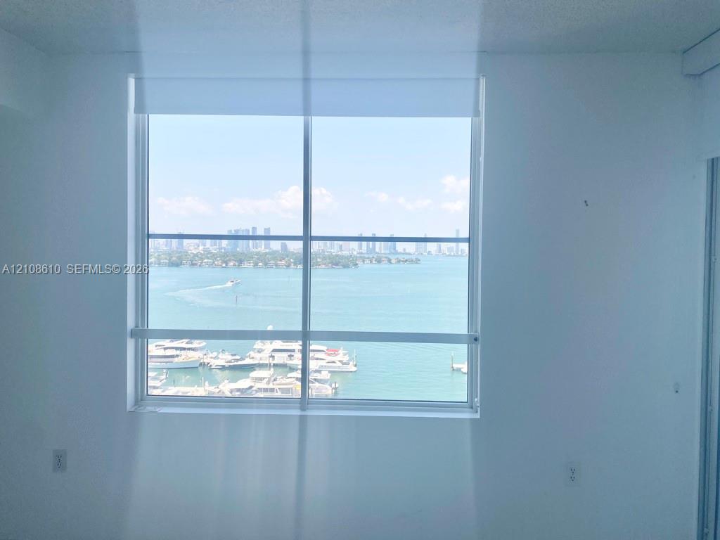 Large picture window with metal frame featuring an expanse of water, marina, and city skyline