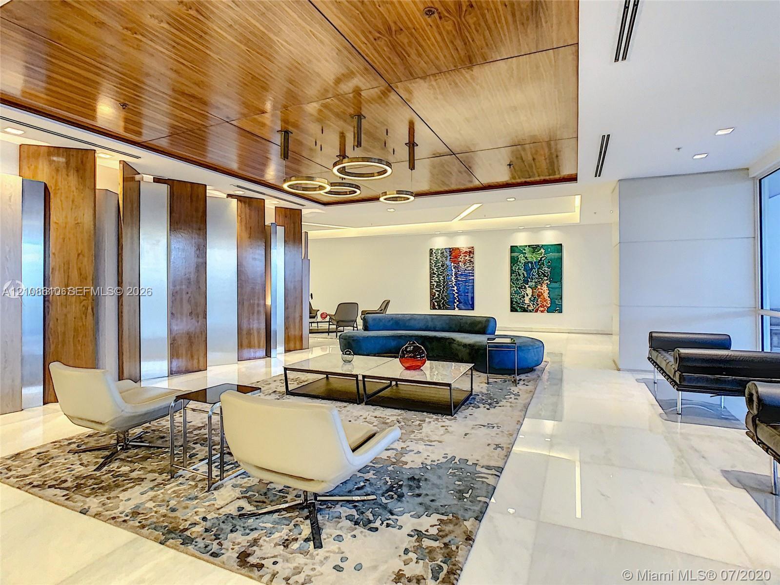 Interior space featuring a high-gloss wood-paneled ceiling, large-format stone flooring, integrated recessed lighting, metallic wall paneling, and contemporary circular pendant light fixtures