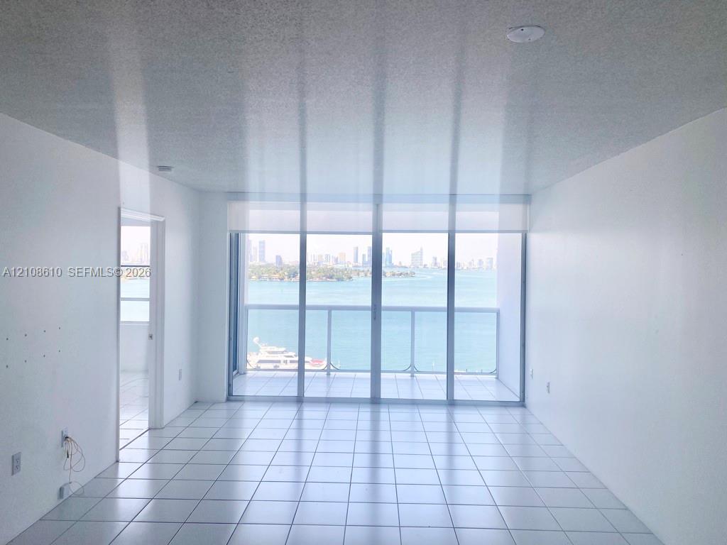 Floor-to-ceiling glass sliding doors, private balcony, ceramic tile flooring, and neutral wall finishes