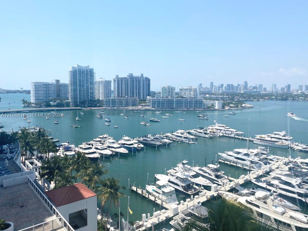 Elevated outdoor terrace featuring a terracotta-tiled roofline, metal railing, and panoramic water, marina, and city skyline scenery