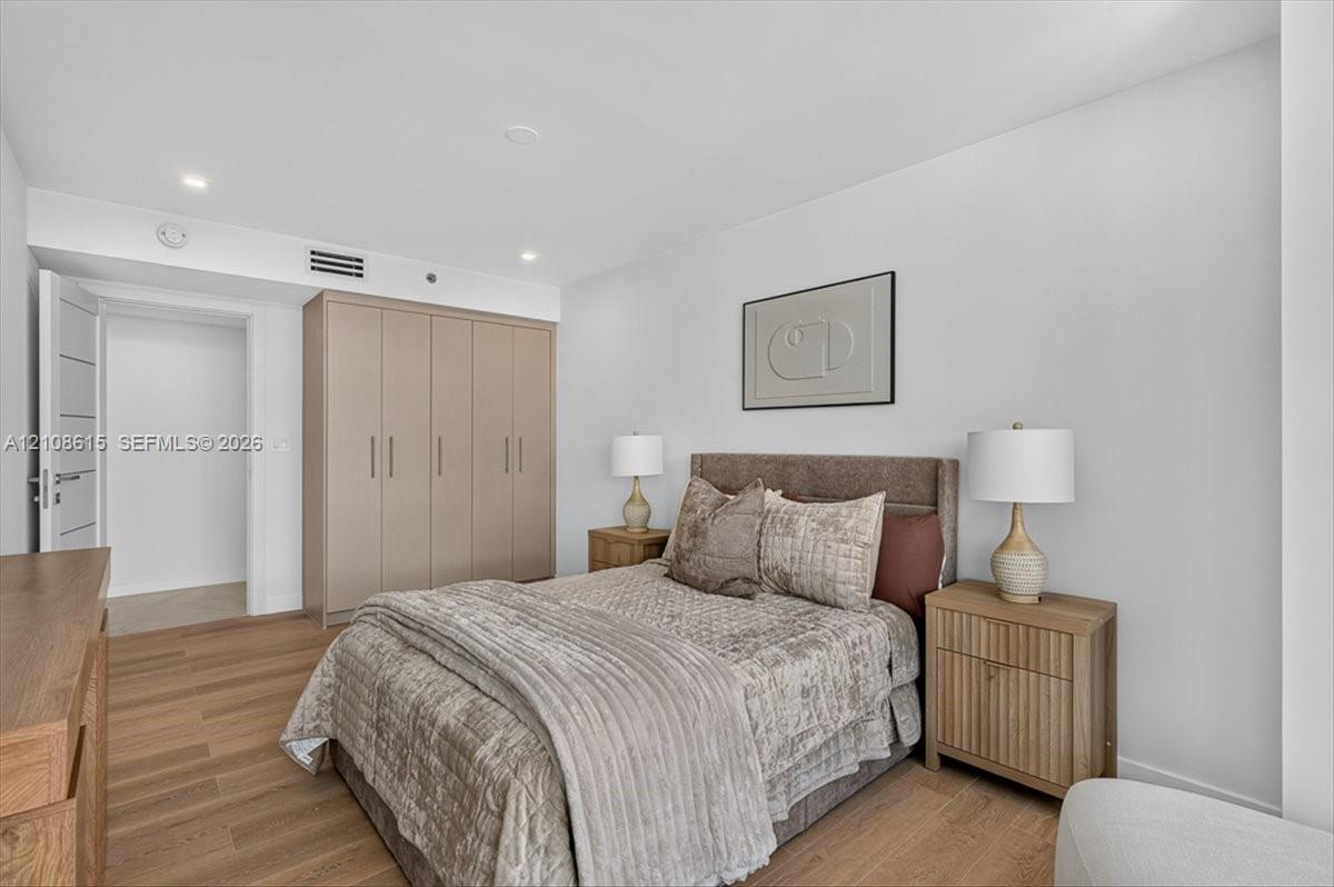 Room featuring wood-finish flooring, recessed lighting, and floor-to-ceiling built-in cabinetry with integrated hardware