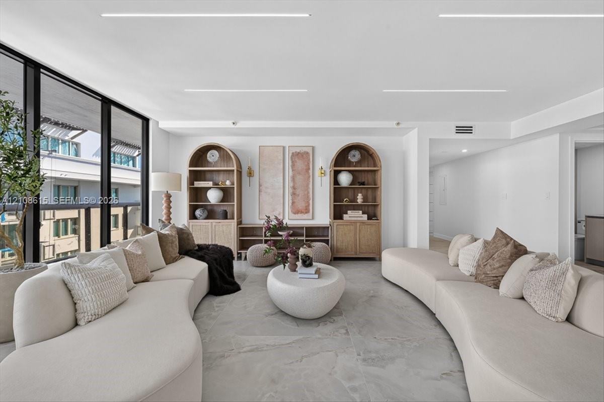 Floor-to-ceiling windows with dark framing, custom built-in arched wood shelving, and large-format stone-finish tile flooring