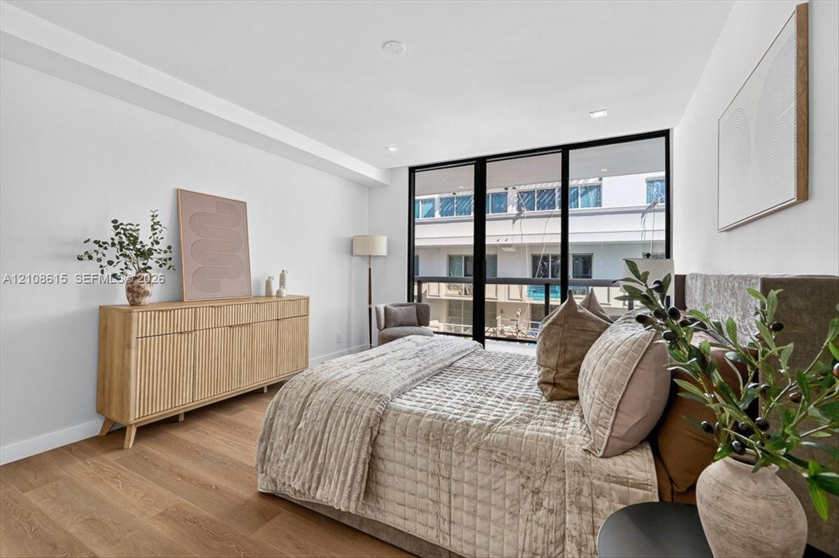 Floor-to-ceiling windows with black frames, wood-finish flooring, and recessed ceiling lighting