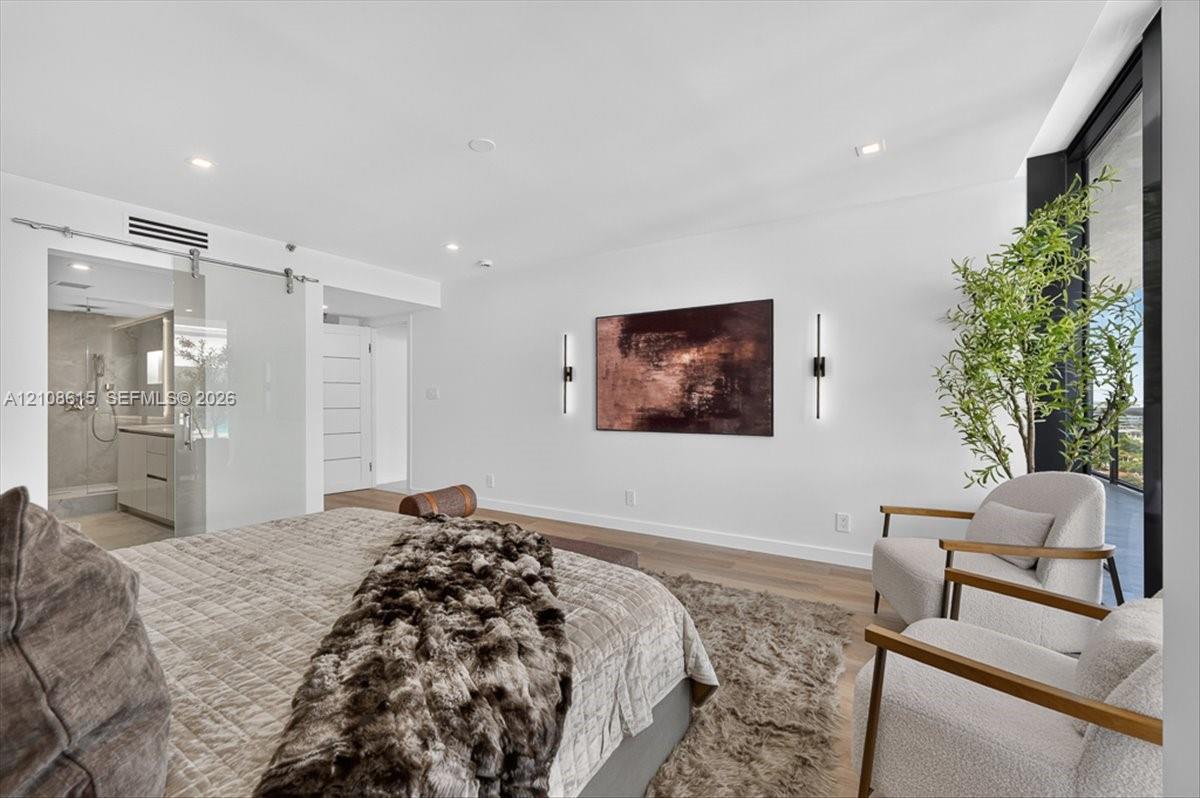 Wood-finish flooring, recessed lighting, wall-mounted linear light fixtures, sliding glass door with a metal track system, and floor-to-ceiling windows