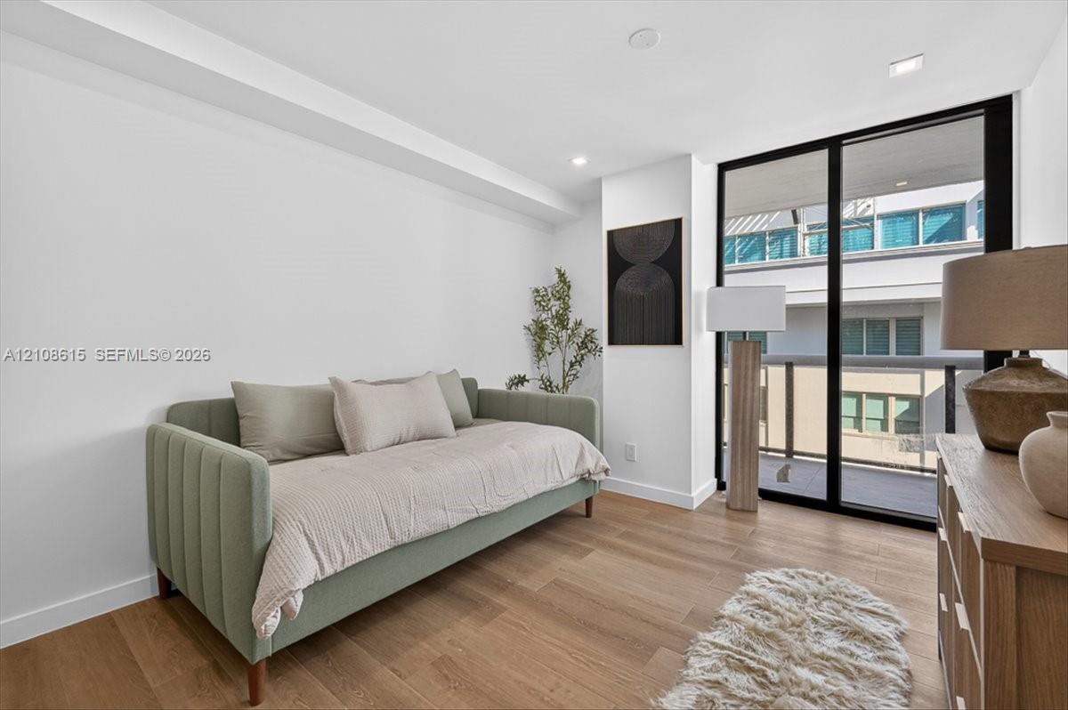 Room featuring wood-finish flooring, recessed lighting, and floor-to-ceiling sliding glass doors opening to an exterior balcony