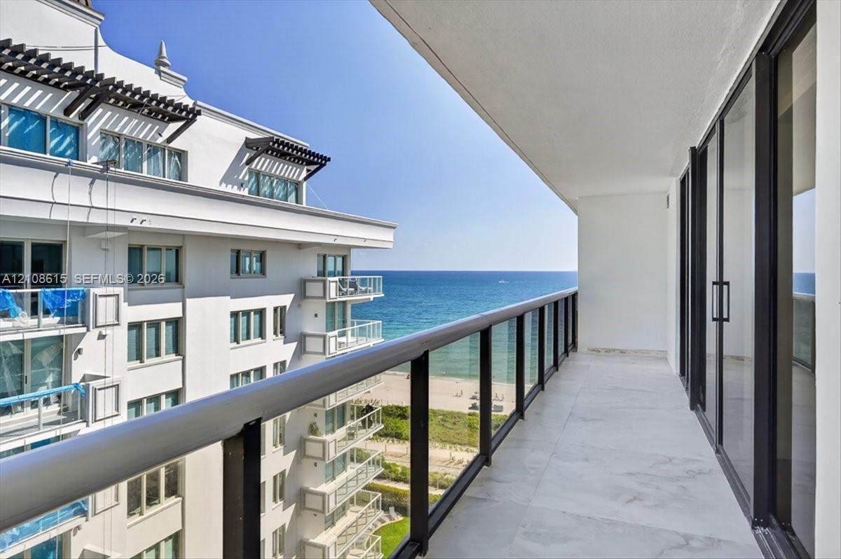 Covered balcony featuring oversized tile flooring, full-height glass sliding doors, and a metal-framed glass railing system