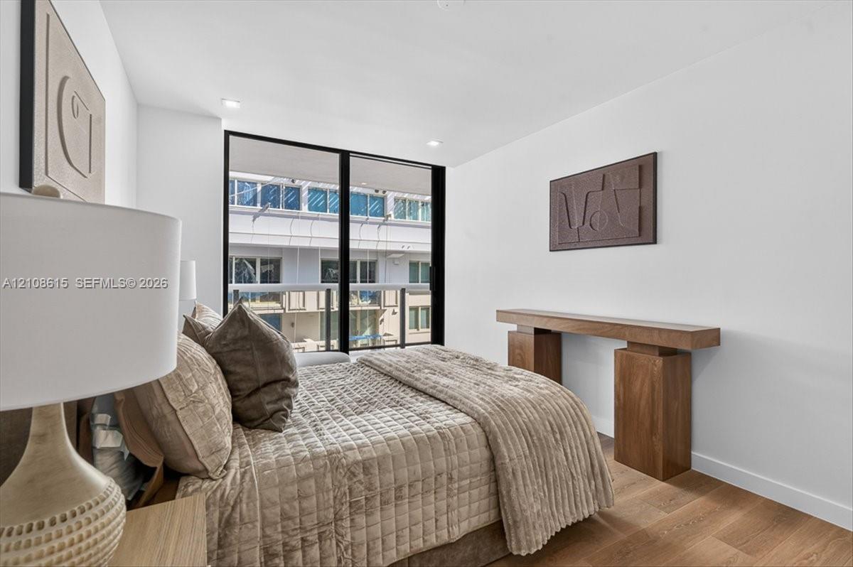 Floor-to-ceiling windows with black framing, wood-finish flooring, and recessed ceiling lighting