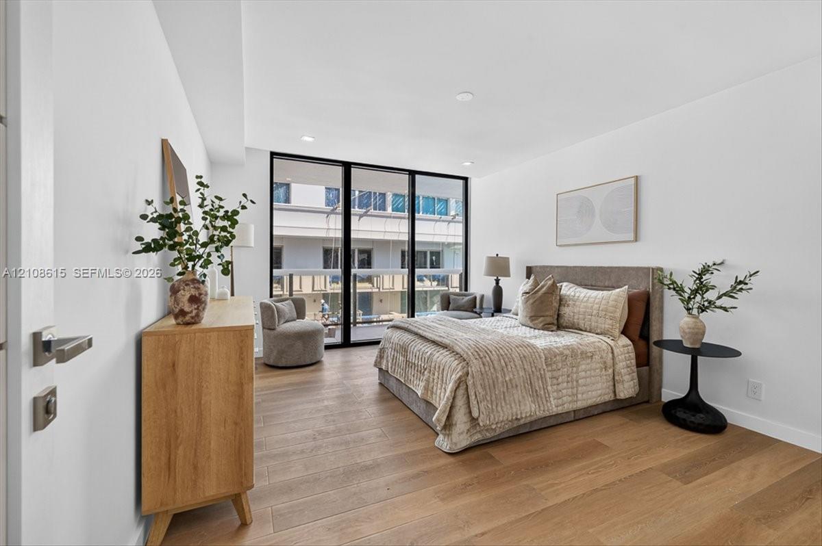 Wood-finish flooring, floor-to-ceiling glass panel door, recessed lighting, and modern hardware fixtures
