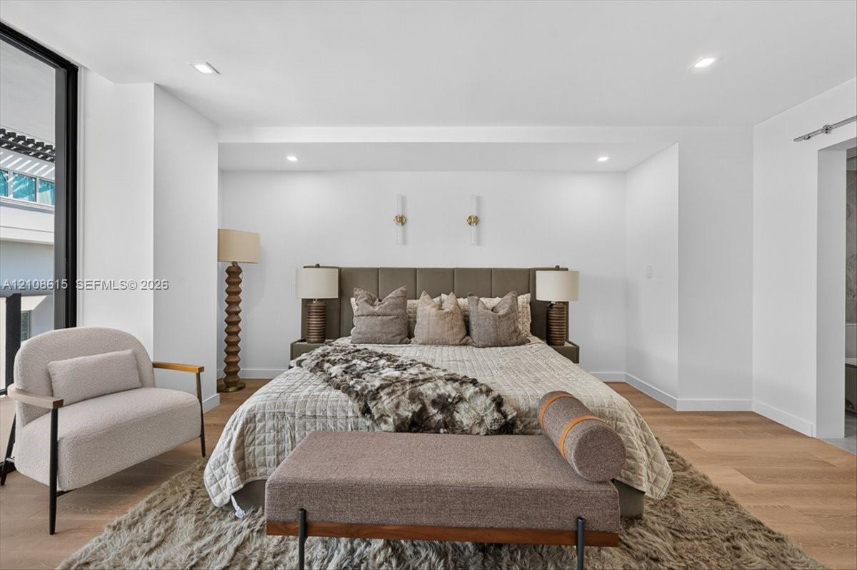 Wood-finish flooring, recessed lighting, and modern vertical wall-mounted fixtures