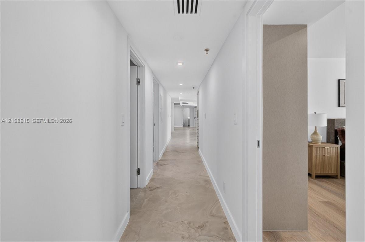 Hallway featuring stone-finish tile flooring, recessed ceiling lighting, and neutral wall tones