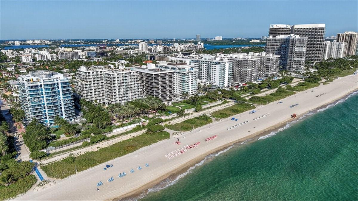 Aerial perspective of waterfront high-rise development featuring direct beach access, coastal shoreline, and proximity to regional urban infrastructure