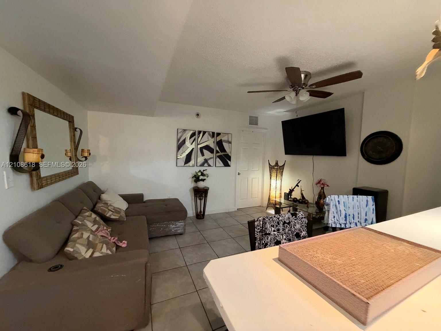 Large-format tile flooring, ceiling fan with integrated lighting, and white interior doors