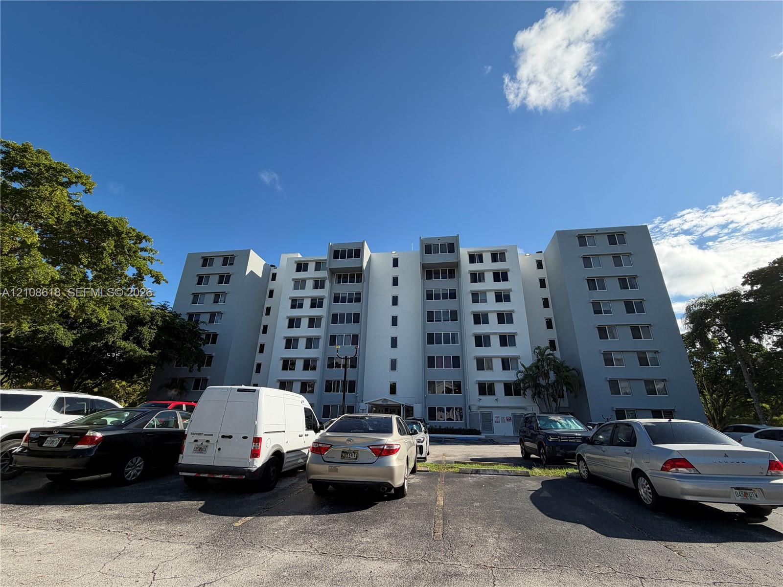 Multi-story residential building featuring a concrete exterior, multi-pane fenestration, and asphalt-paved surface parking
