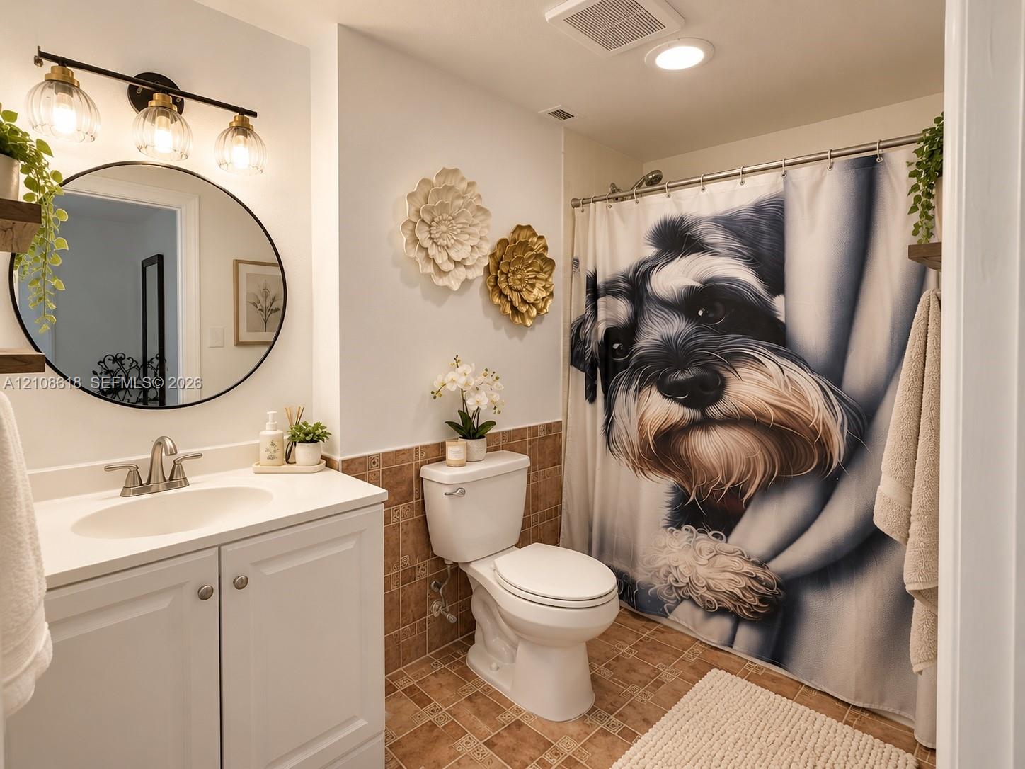 Bathroom featuring a vanity with white cabinetry, a round mirror, a three-light fixture, and tile flooring