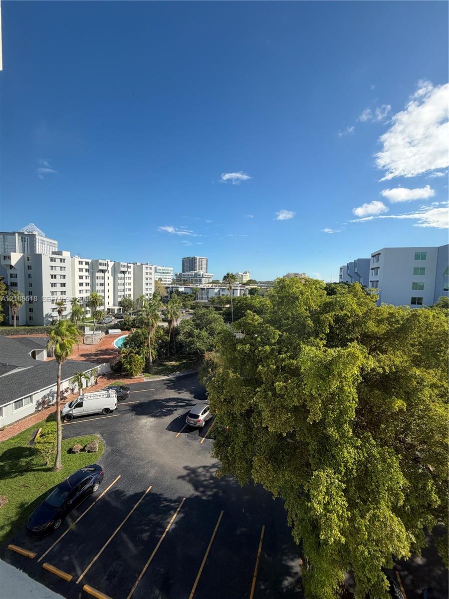 Elevated outdoor perspective featuring mature landscaping, paved surface parking, and regional architecture