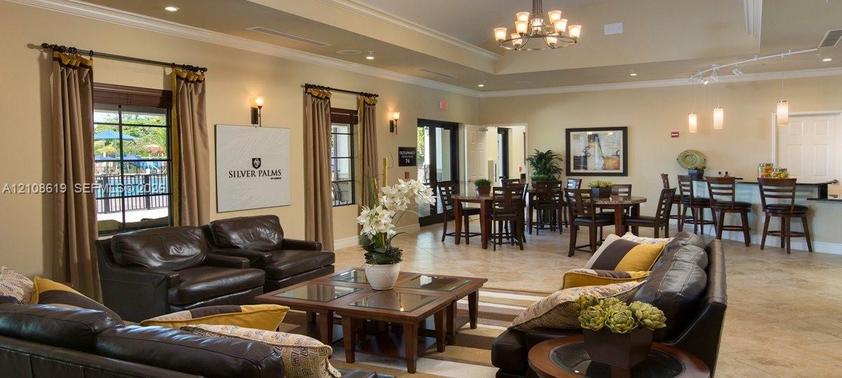 Open-concept communal area featuring tile flooring, recessed and decorative chandelier lighting, coffered ceilings, and a built-in bar