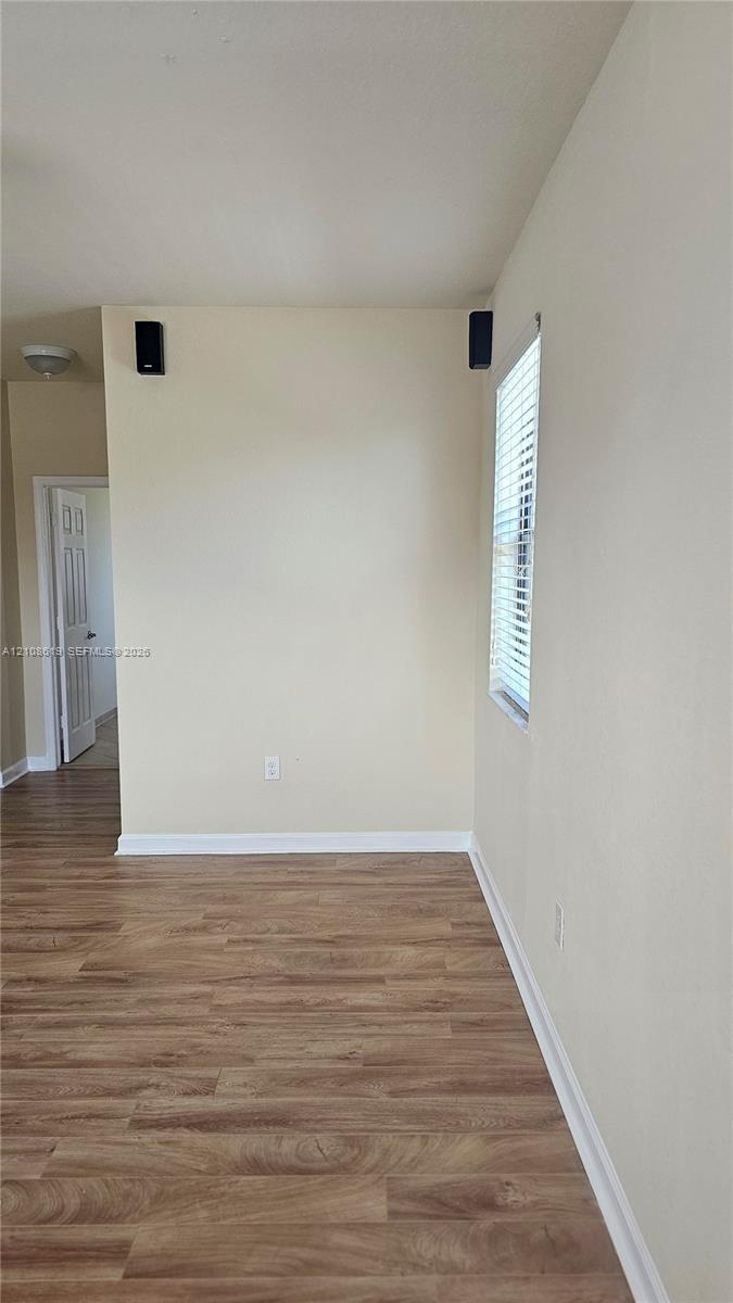 Interior space featuring wood-finish flooring, a neutral wall palette, and a window with horizontal blinds