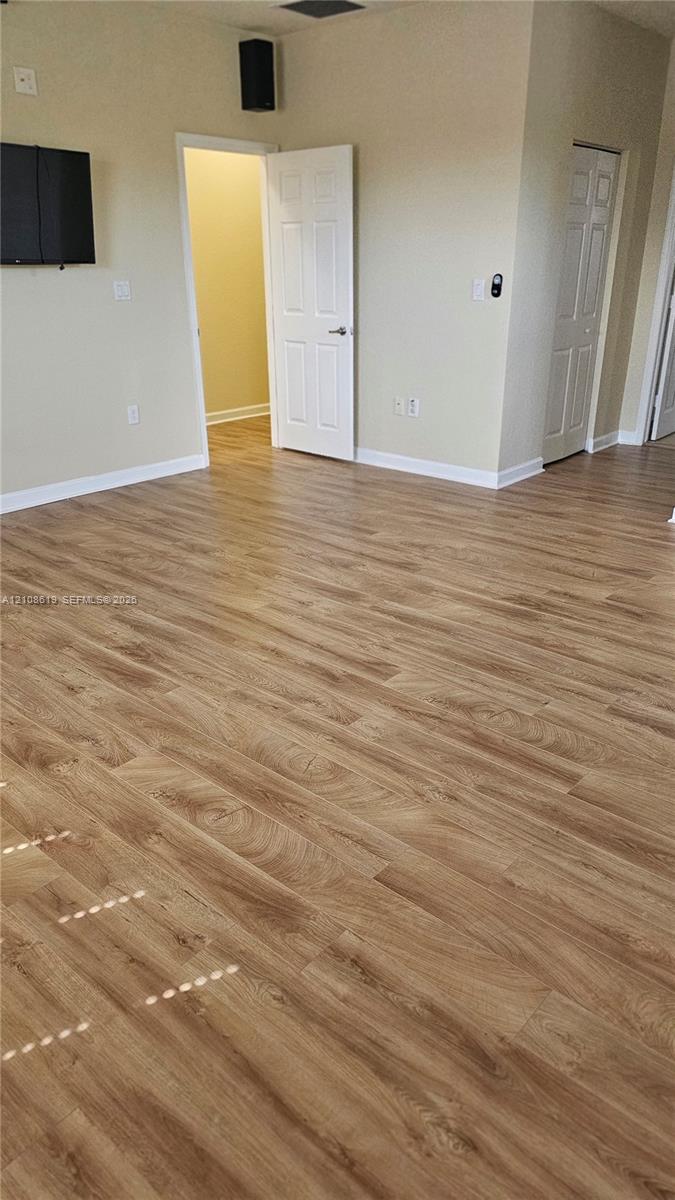 Interior space featuring wood-finish flooring, neutral wall tones, multi-panel interior doors, and a wall-mounted speaker