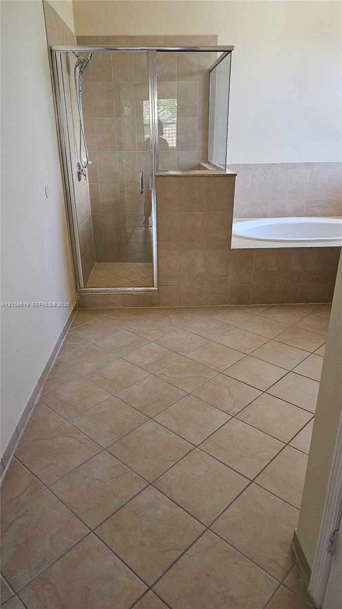 Ceramic tile flooring, built-in soaking tub with a tiled surround, and a walk-in glass-enclosed shower with a handheld showerhead