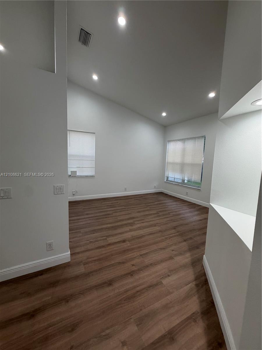 Vaulted ceiling with recessed lighting, wood-finish flooring, and built-in display niche