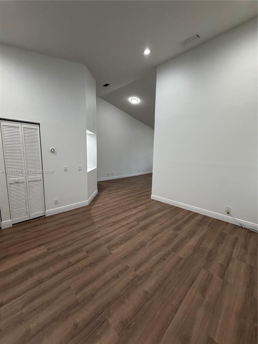 Interior space featuring vaulted ceilings, wood-finish flooring, recessed lighting, and a built-in wall niche with closet storage