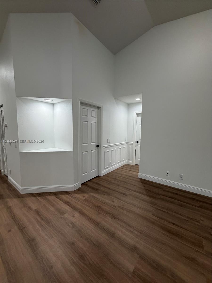 Vaulted ceilings, wood-finish flooring, recessed architectural niche with integrated lighting, and wainscoting detailing