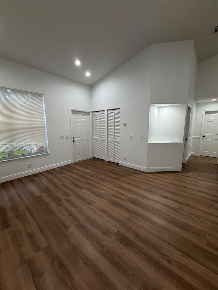 Vaulted ceilings, wood-finish flooring, recessed lighting, built-in recessed wall shelving, and louvered-panel closet doors