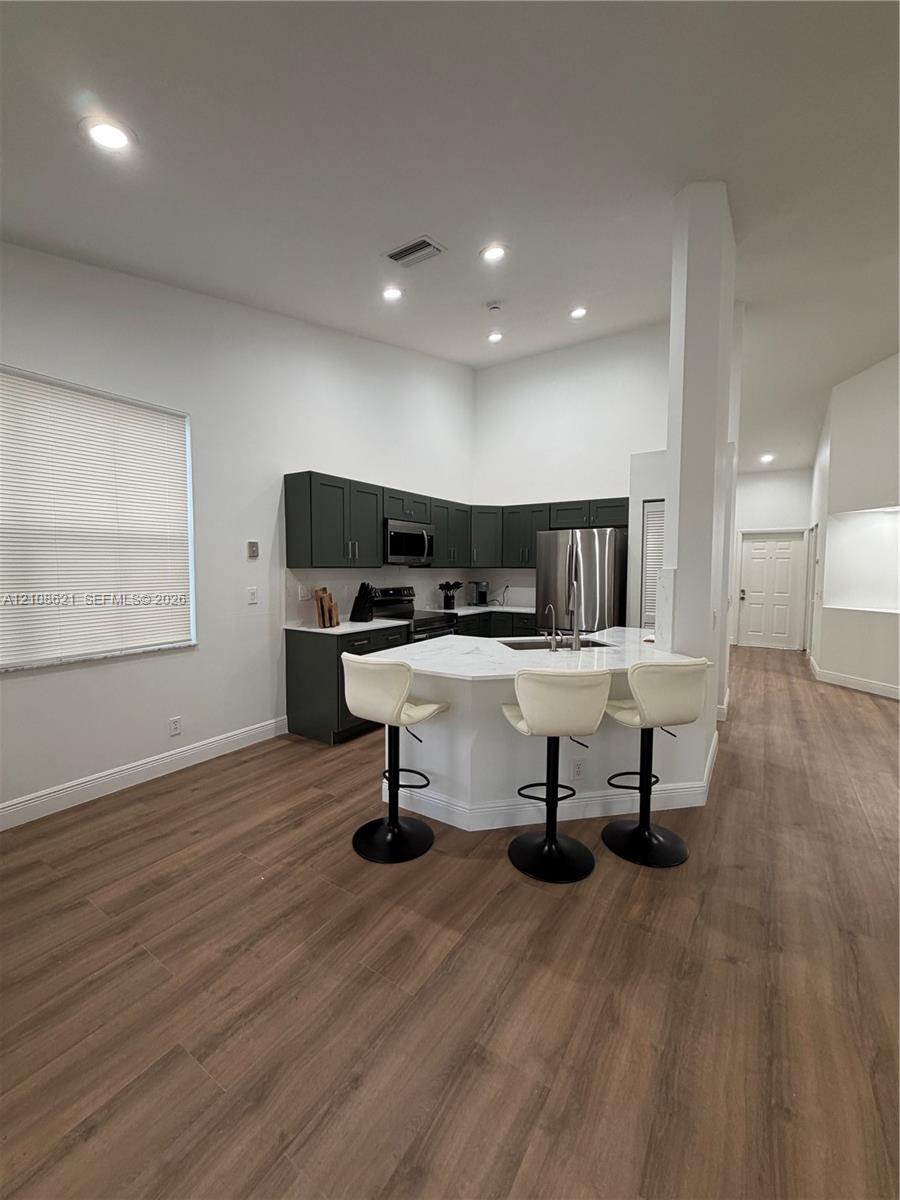 Kitchen featuring dark-toned cabinetry, light-toned countertops, wood-finish flooring, and recessed ceiling lighting