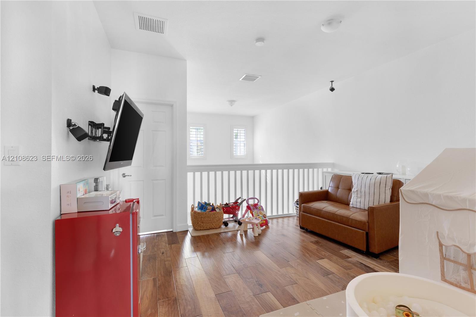 Wood-finish flooring, white spindle railing, interior shutters, and recessed lighting