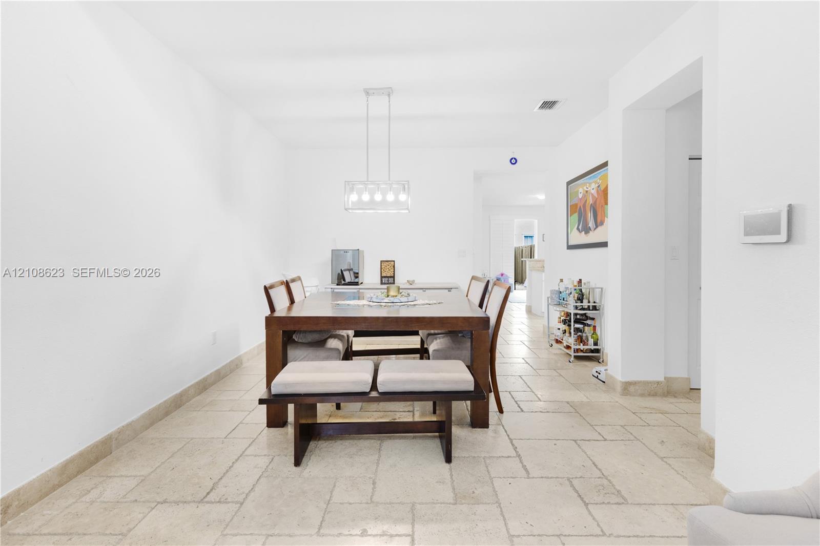 Natural stone flooring in a rectangular tile pattern, finished with a contemporary multi-light linear pendant fixture