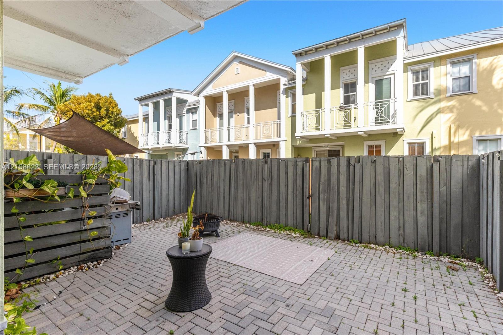 Paved brick patio enclosed by a privacy fence, featuring a permanent slatted wood partition