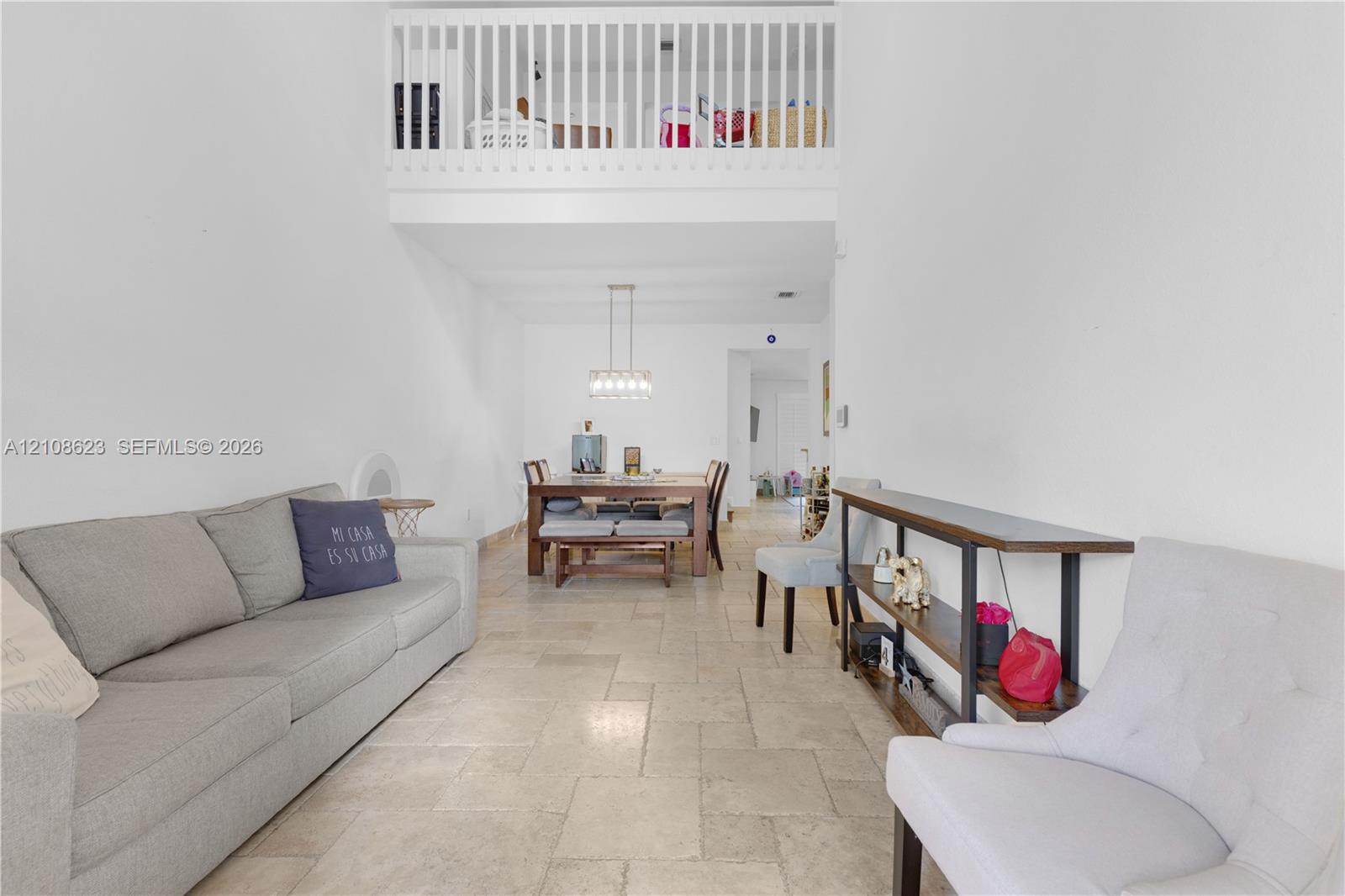 Double-height ceilings, tiled flooring, and an elevated interior mezzanine with a wooden-rail banister