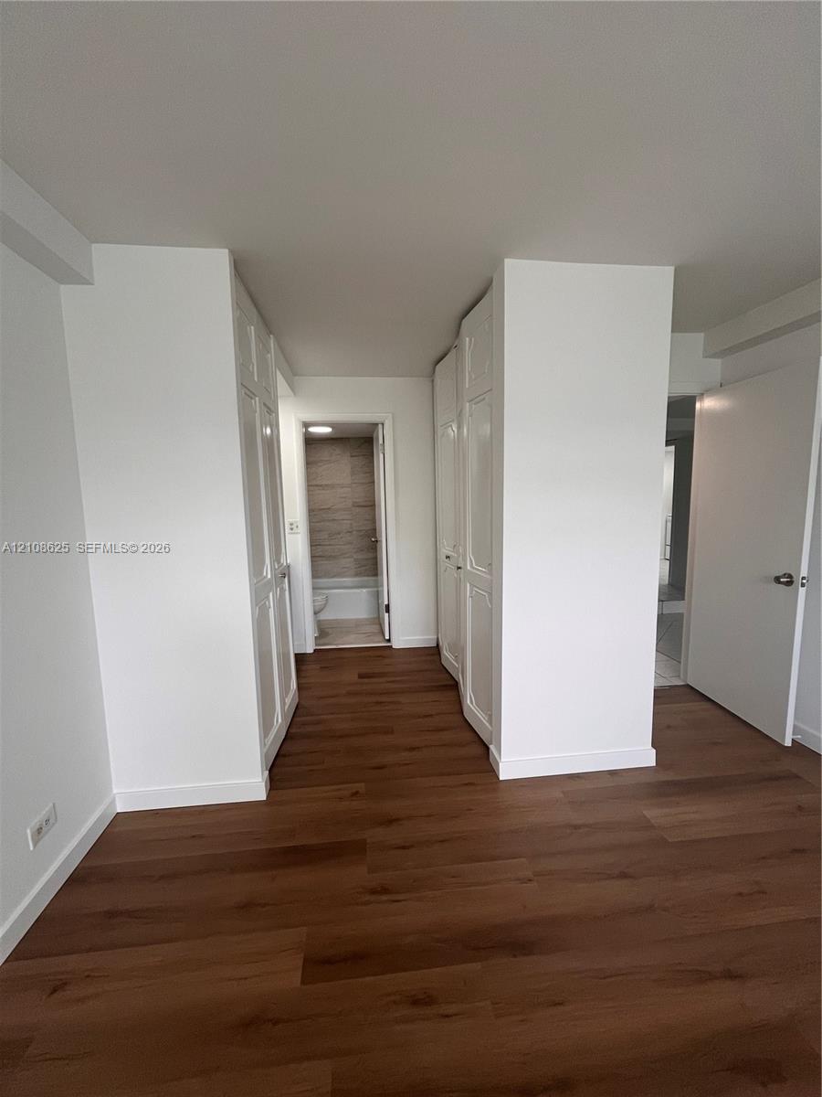 Interior space featuring wood-finish flooring, two sets of white panel doors, and neutral wall tones