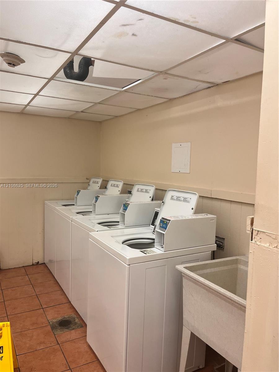 Laundry room featuring multiple top-load washers, a drop-in utility sink, and tile flooring