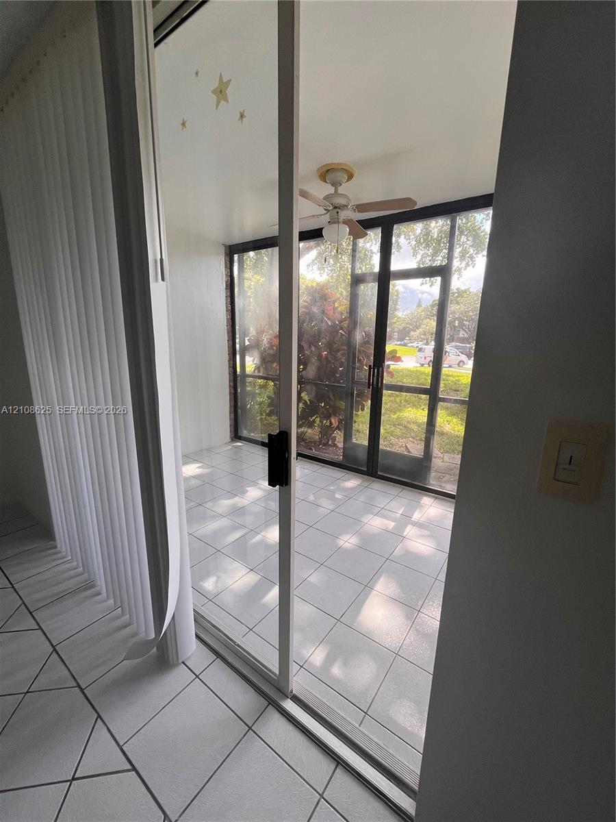 Enclosed patio featuring tile flooring, a ceiling fan, and black-framed screen panels