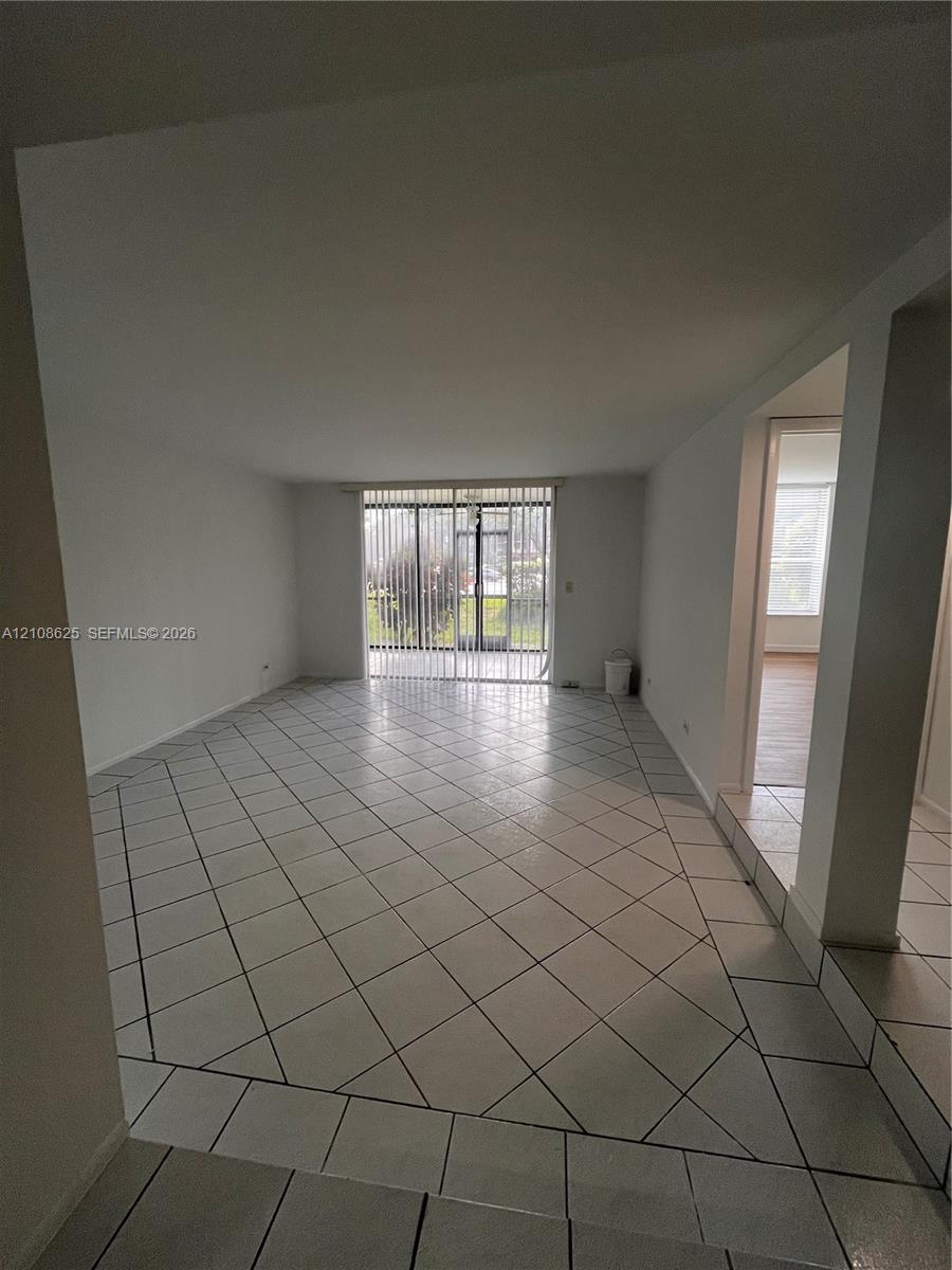 Open-concept interior featuring diagonal tile flooring and sliding glass doors with vertical blinds