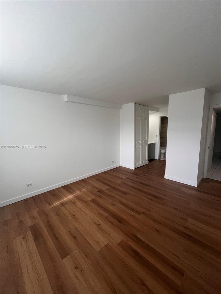 Interior space featuring wood-finish flooring, white walls, and built-in closet cabinetry