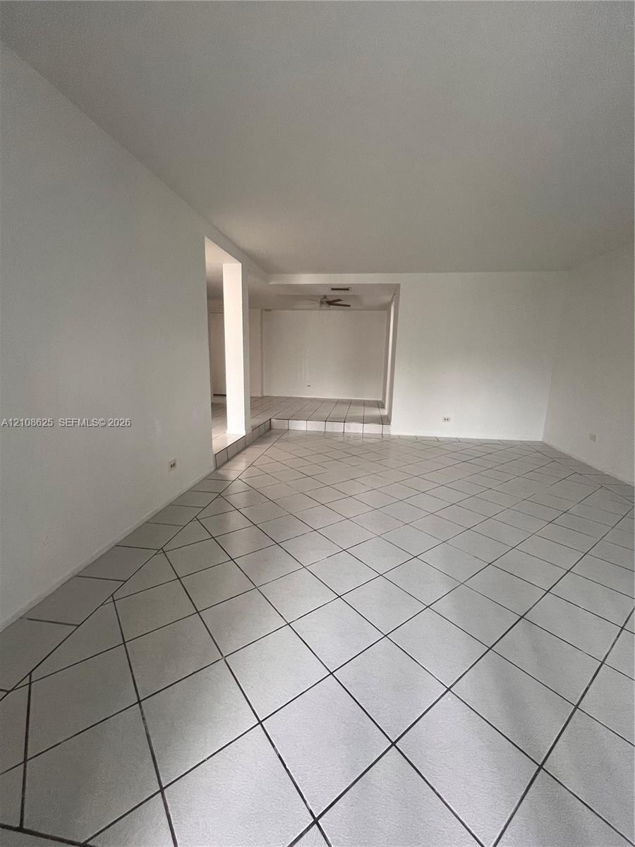 Spacious interior featuring large-format diagonal tile flooring, a recessed ceiling design, and elevated platform section